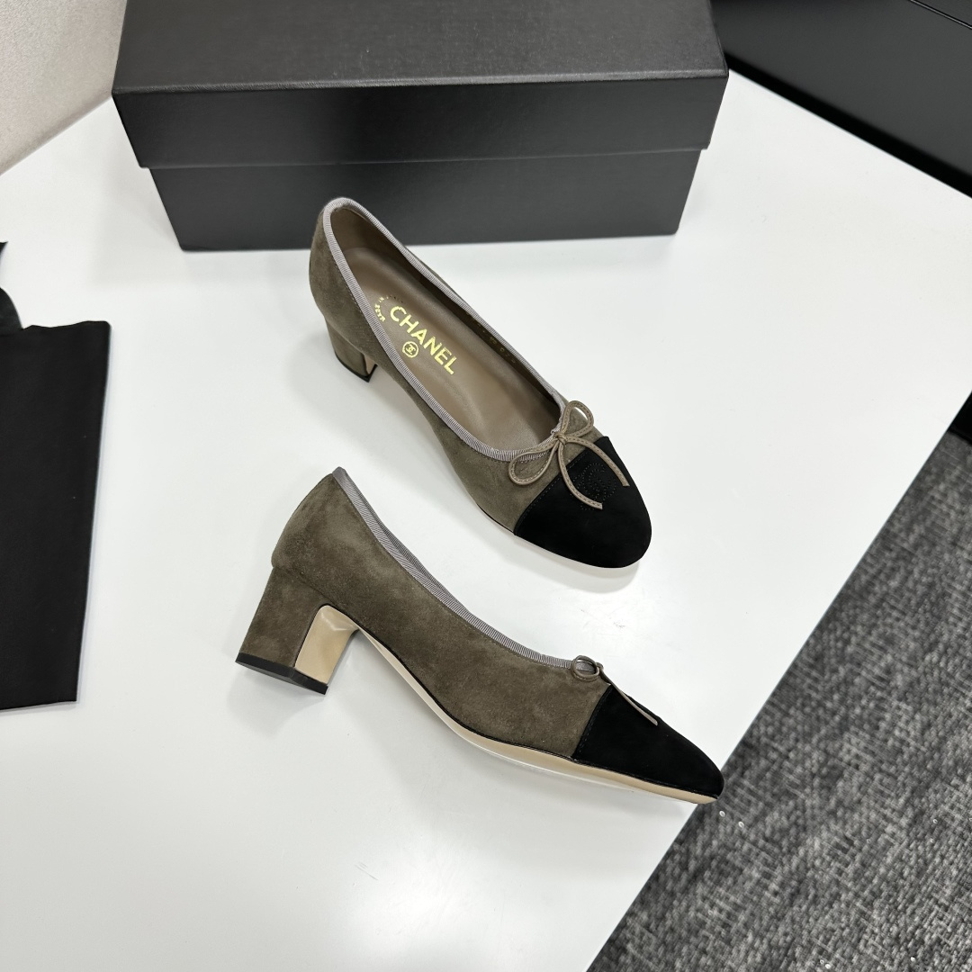 A pair of Chanel two-tone khaki and black suede pumps with a block heel and bow detail displayed on a black box. - Hình 7