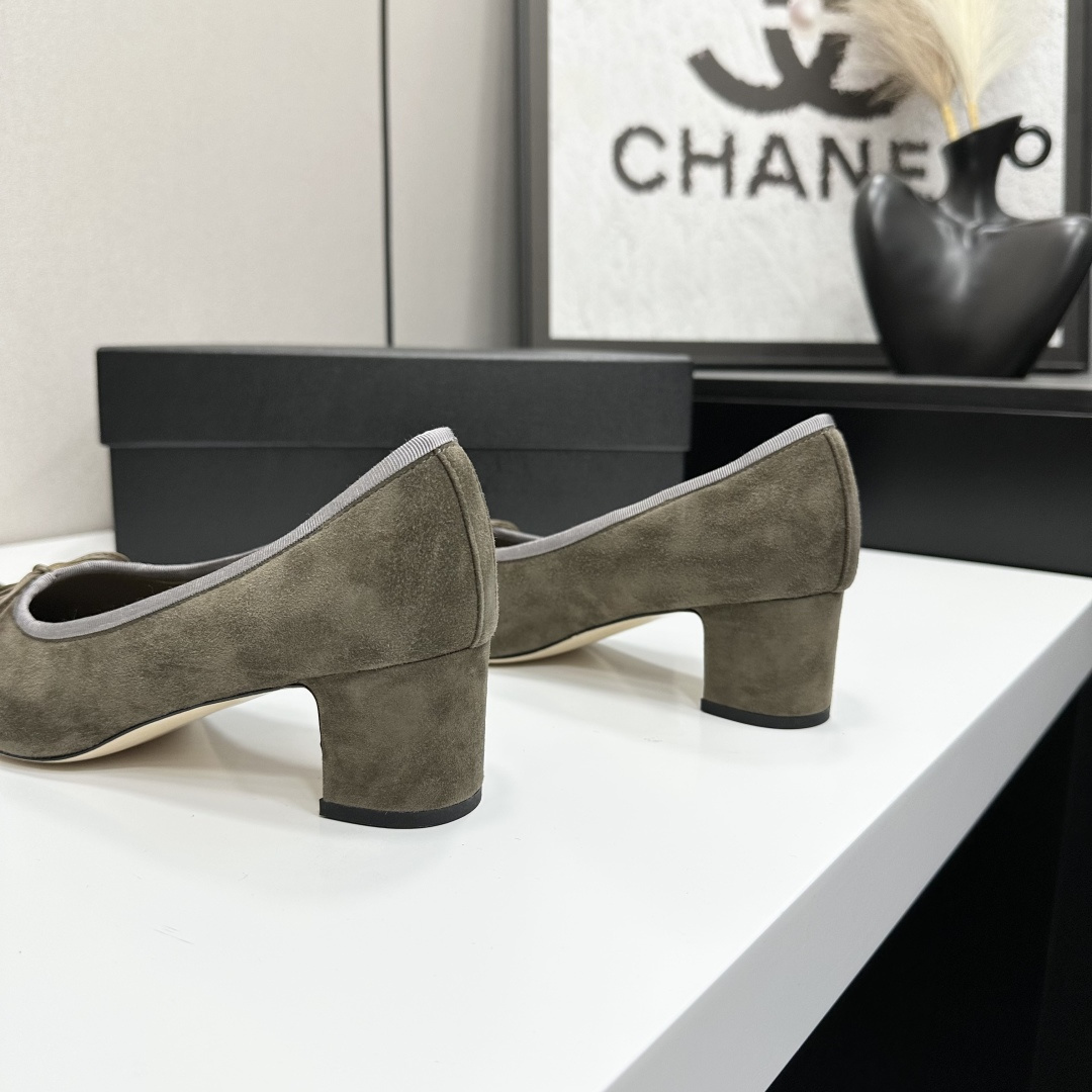 A pair of Chanel two-tone khaki and black suede pumps with a block heel and bow detail displayed on a black box. - Hình 6