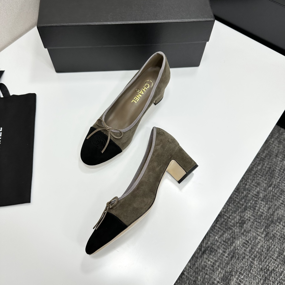 A pair of Chanel two-tone khaki and black suede pumps with a block heel and bow detail displayed on a black box. - Hình 5