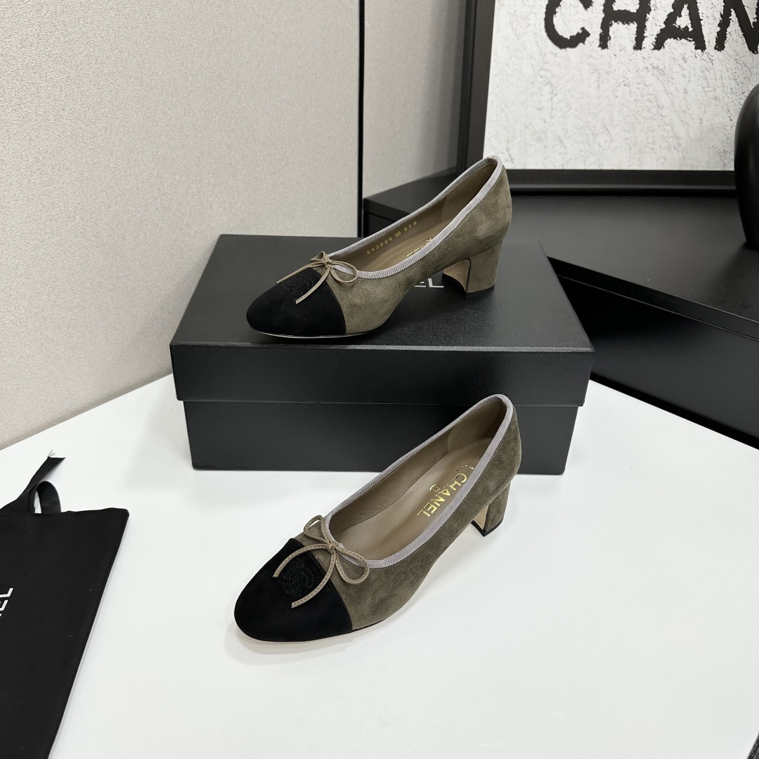 A pair of Chanel two-tone khaki and black suede pumps with a block heel and bow detail displayed on a black box. - Hình 2