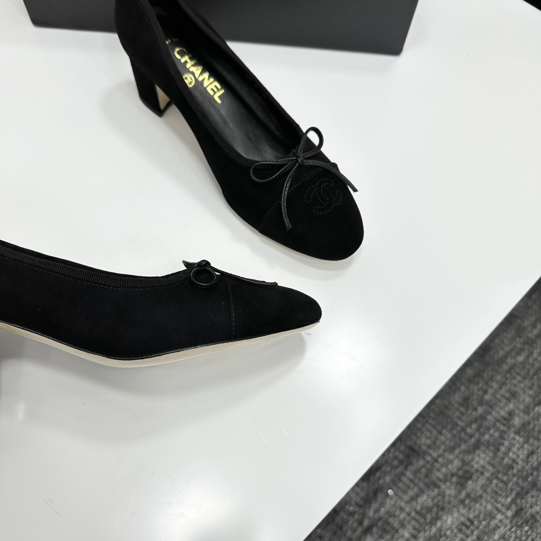 Pair of Chanel black suede block heel pumps with a delicate bow and interlocking CC logo on the toe cap sitting on a black box. - Hình 9