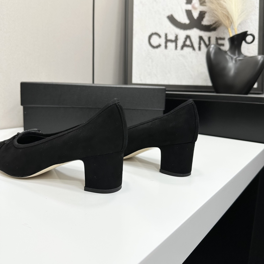 Pair of Chanel black suede block heel pumps with a delicate bow and interlocking CC logo on the toe cap sitting on a black box. - Hình 6