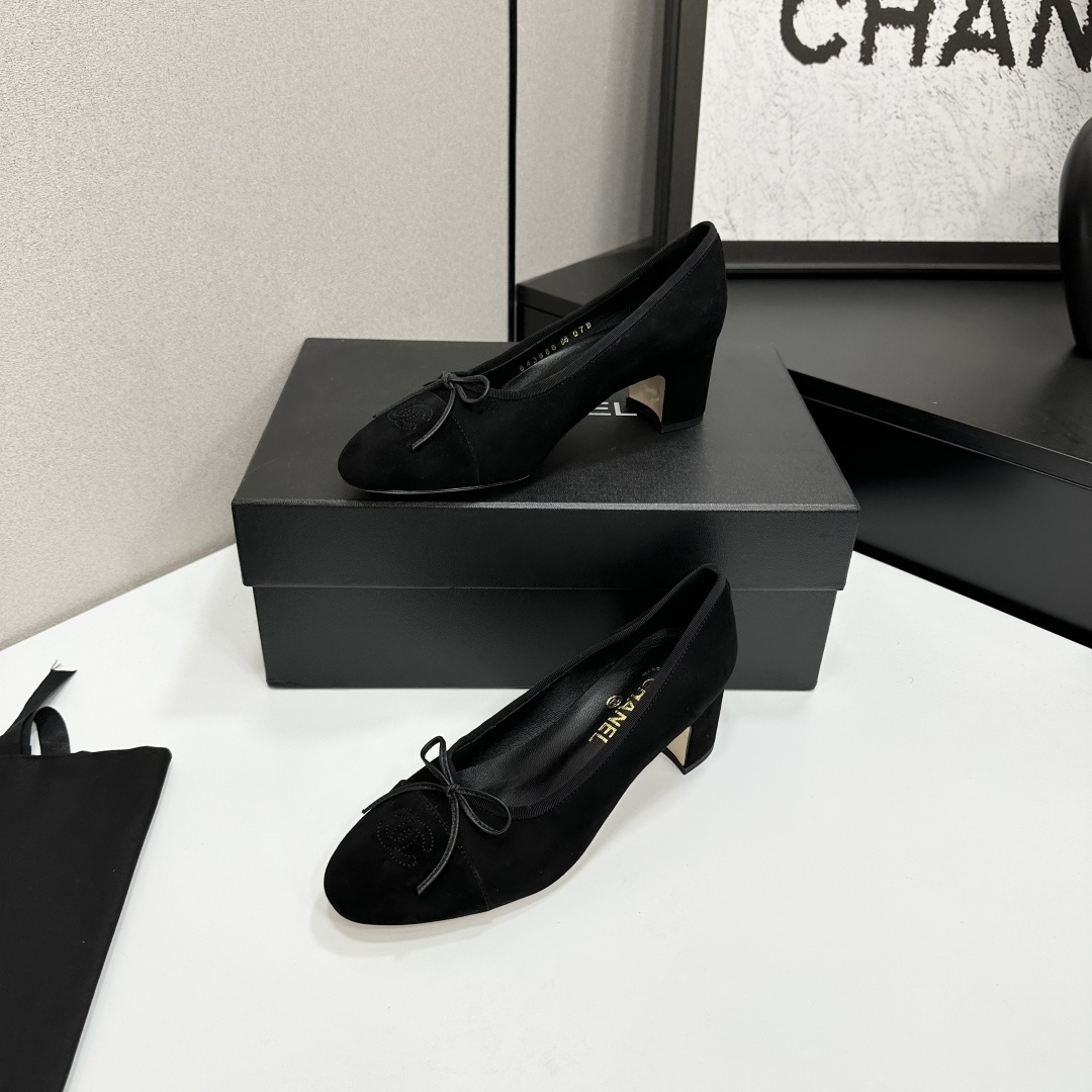 Pair of Chanel black suede block heel pumps with a delicate bow and interlocking CC logo on the toe cap sitting on a black box. - Hình 2