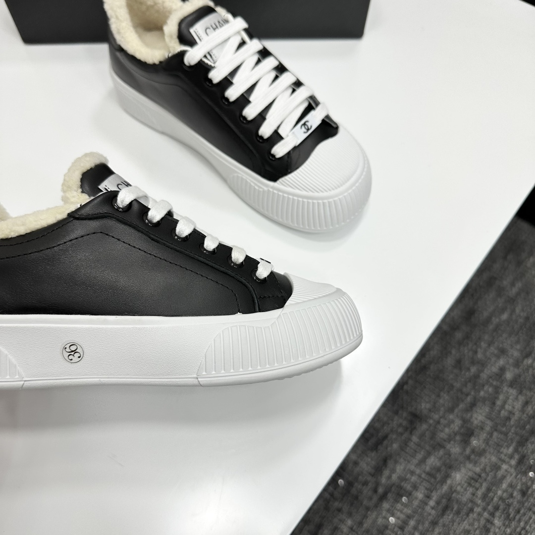 Side view of Chanel black leather sneakers with white shearling lining and chunky platform soles on a black display box. - Hình 10