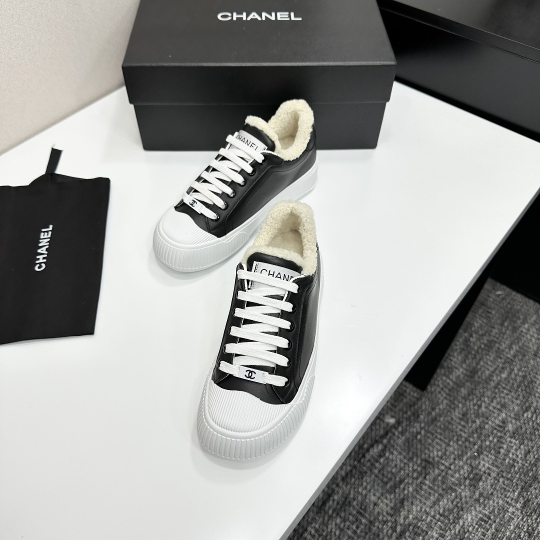 Side view of Chanel black leather sneakers with white shearling lining and chunky platform soles on a black display box. - Hình 6