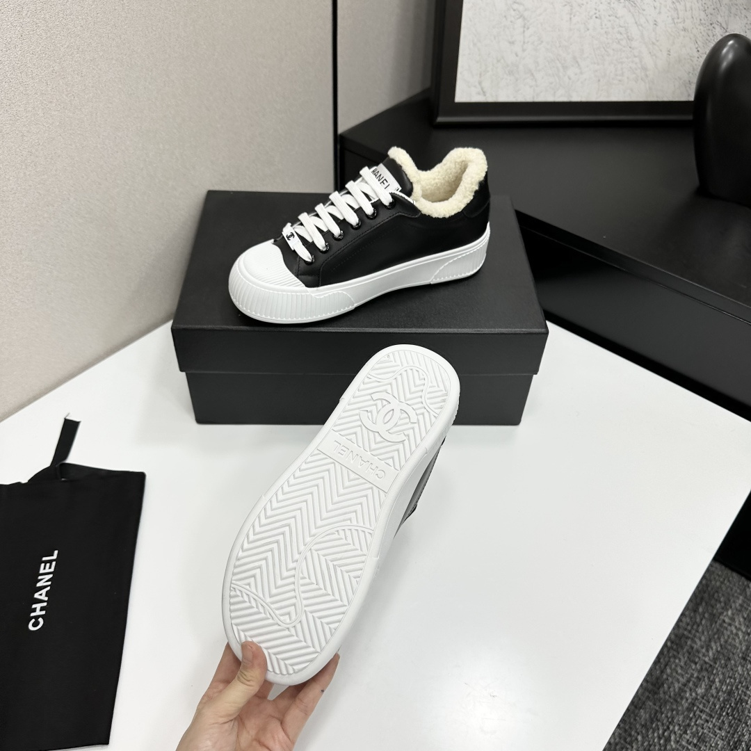 Side view of Chanel black leather sneakers with white shearling lining and chunky platform soles on a black display box. - Hình 5