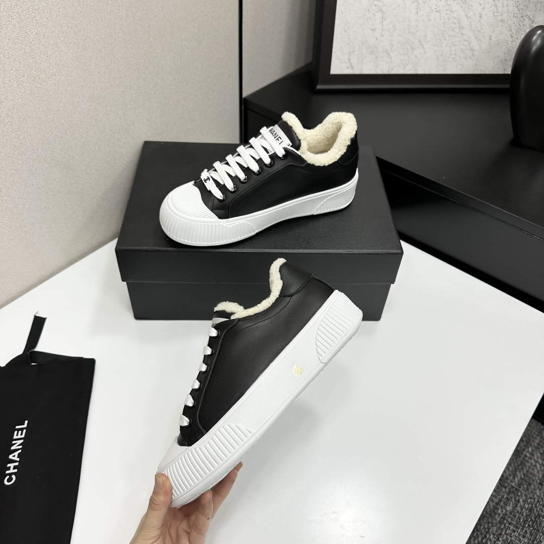 Side view of Chanel black leather sneakers with white shearling lining and chunky platform soles on a black display box. - Hình 4