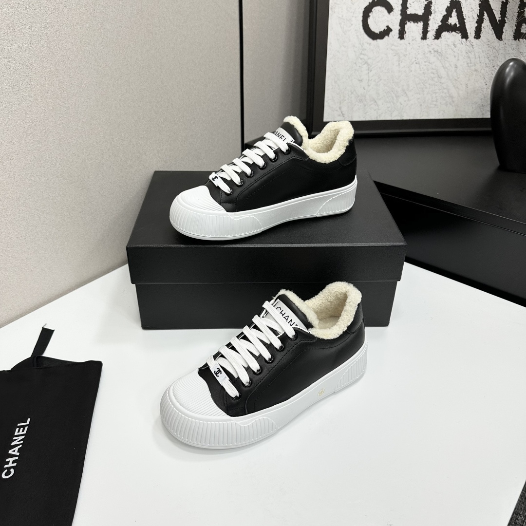 Side view of Chanel black leather sneakers with white shearling lining and chunky platform soles on a black display box. - Hình 3