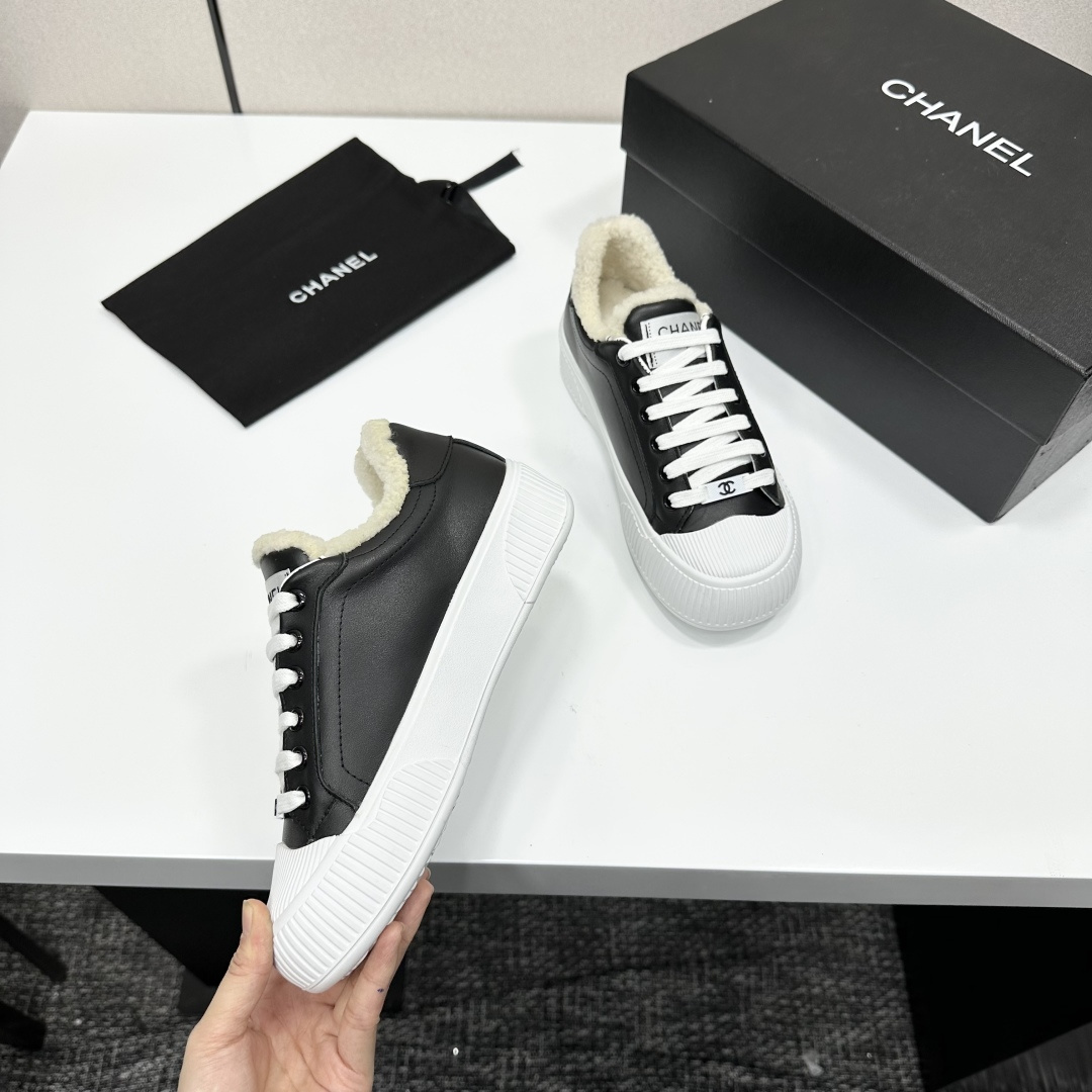 Side view of Chanel black leather sneakers with white shearling lining and chunky platform soles on a black display box. - Hình 2