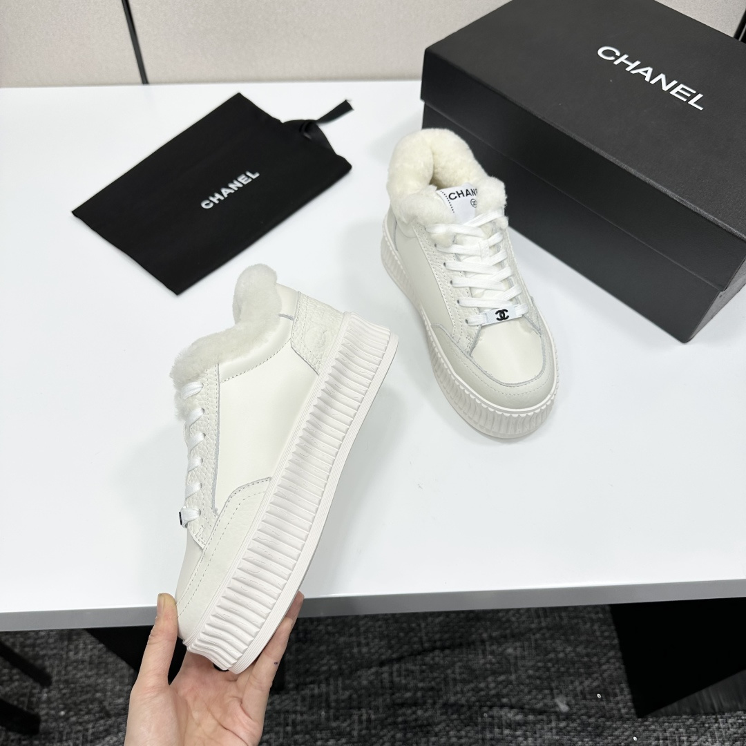 A pair of Chanel white platform sneakers with white fur lining and iconic logo details displayed on a black box. - Hình 9