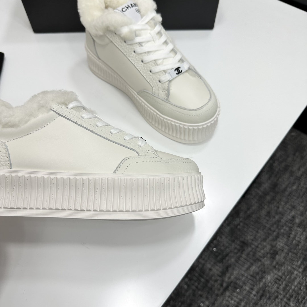 A pair of Chanel white platform sneakers with white fur lining and iconic logo details displayed on a black box. - Hình 8