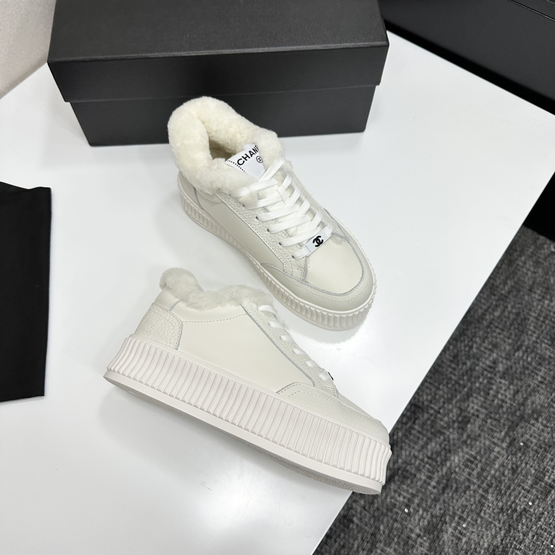 A pair of Chanel white platform sneakers with white fur lining and iconic logo details displayed on a black box. - Hình 7