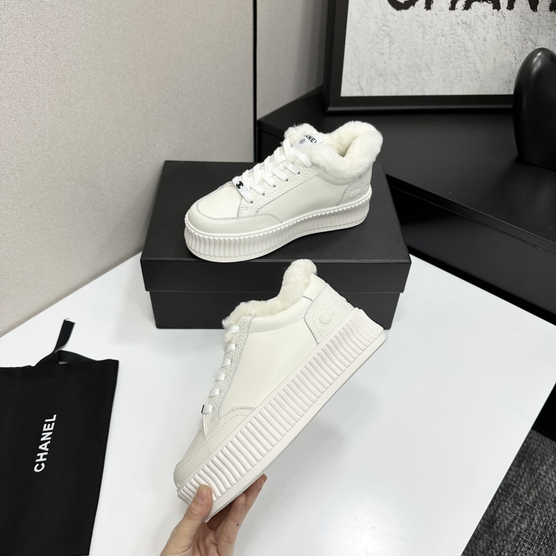 A pair of Chanel white platform sneakers with white fur lining and iconic logo details displayed on a black box. - Hình 3