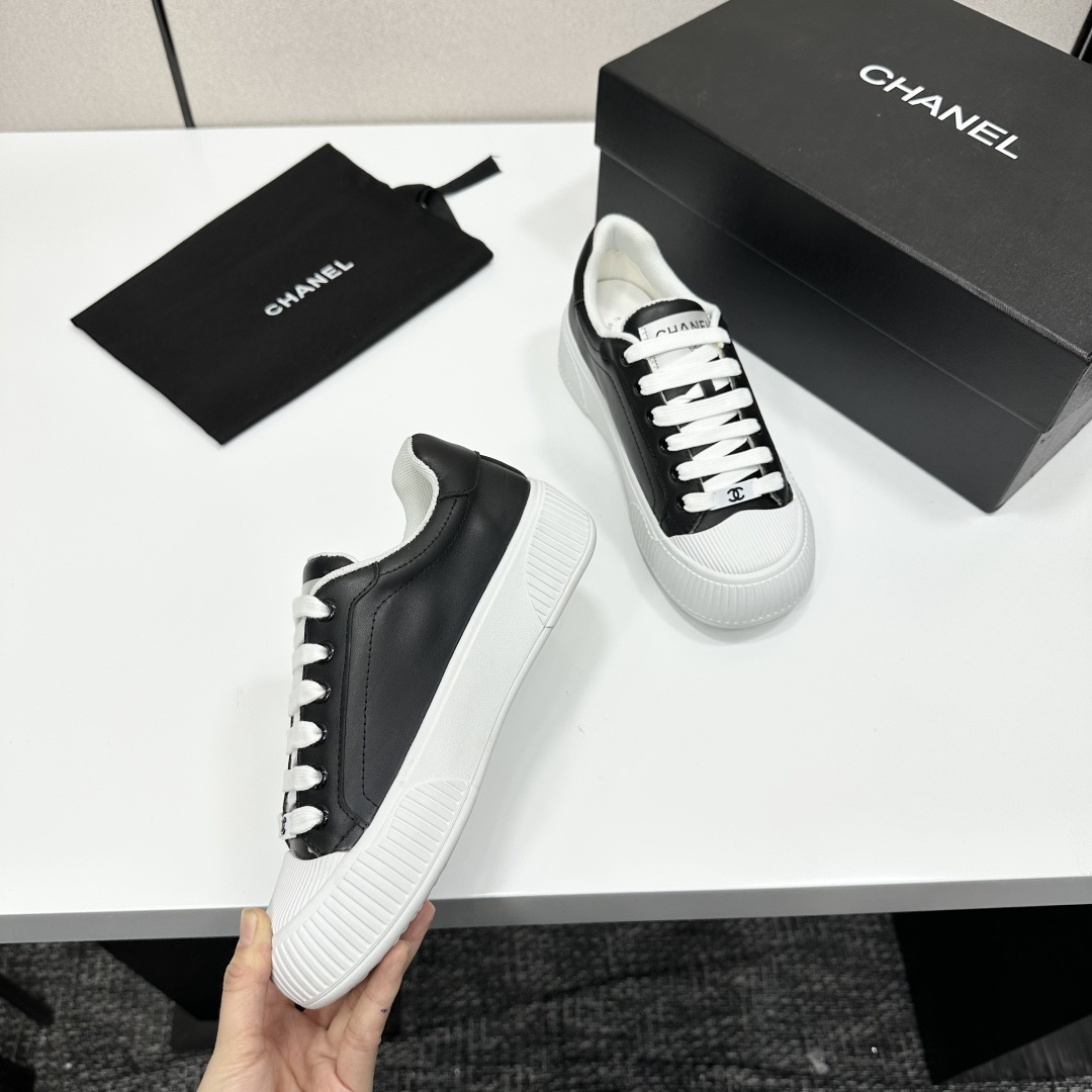 Side view of Chanel black and white platform sneakers with ribbed soles on a black designer box - Hình 9