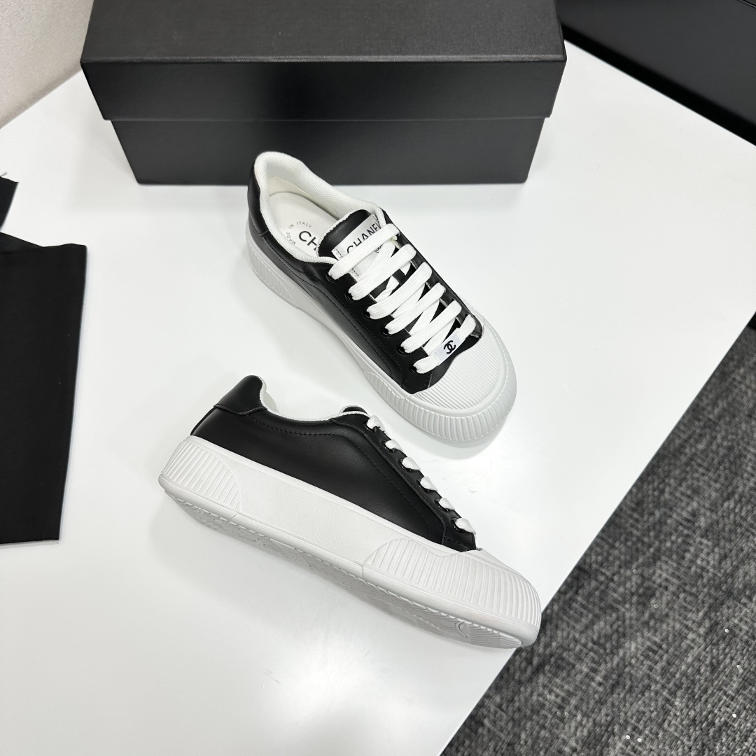 Side view of Chanel black and white platform sneakers with ribbed soles on a black designer box - Hình 8