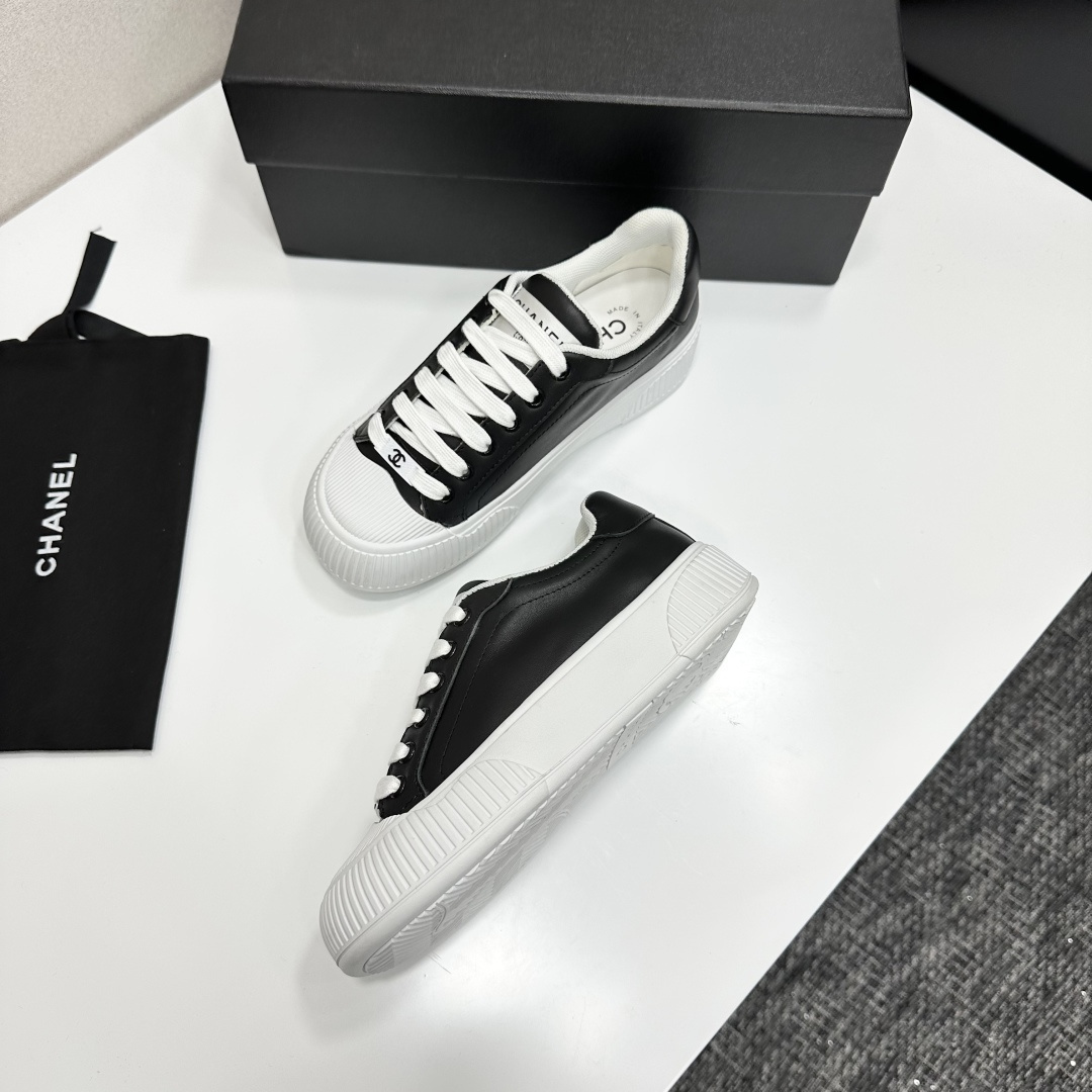 Side view of Chanel black and white platform sneakers with ribbed soles on a black designer box - Hình 6