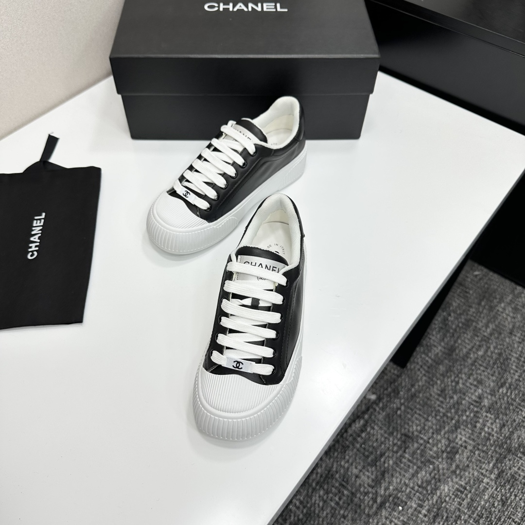 Side view of Chanel black and white platform sneakers with ribbed soles on a black designer box - Hình 5