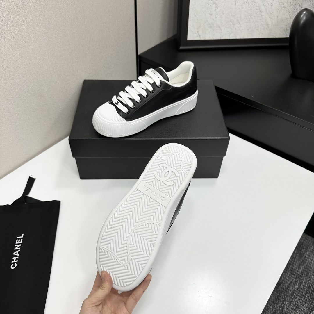 Side view of Chanel black and white platform sneakers with ribbed soles on a black designer box - Hình 4