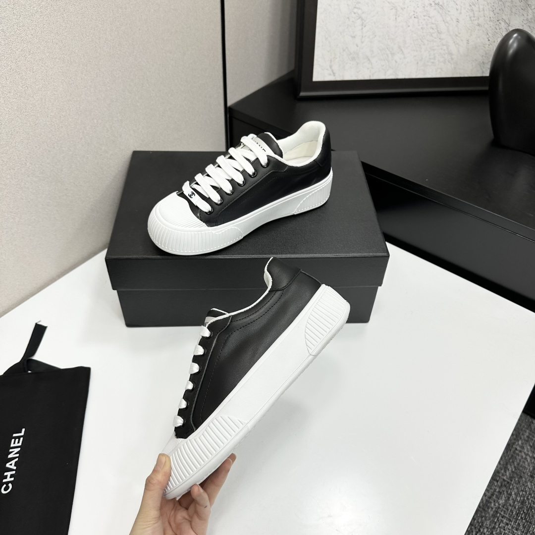 Side view of Chanel black and white platform sneakers with ribbed soles on a black designer box - Hình 3