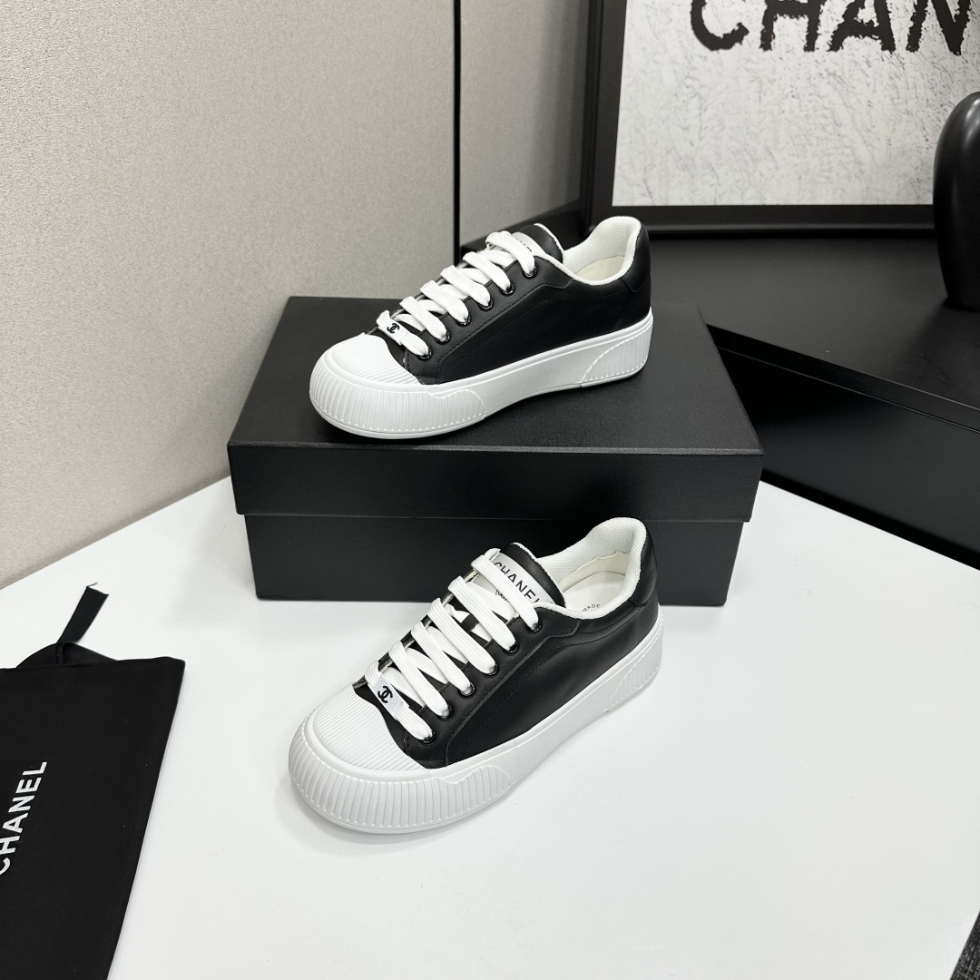 Side view of Chanel black and white platform sneakers with ribbed soles on a black designer box - Hình 2
