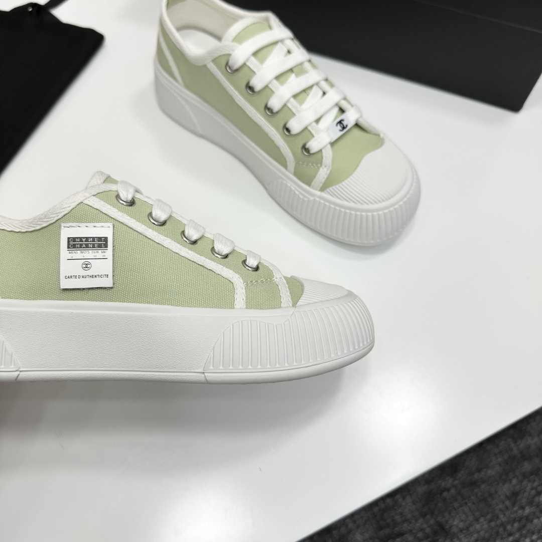 A pair of Chanel luxury green canvas platform sneakers with white ribbed soles and laces displayed on a black box. - Hình 9
