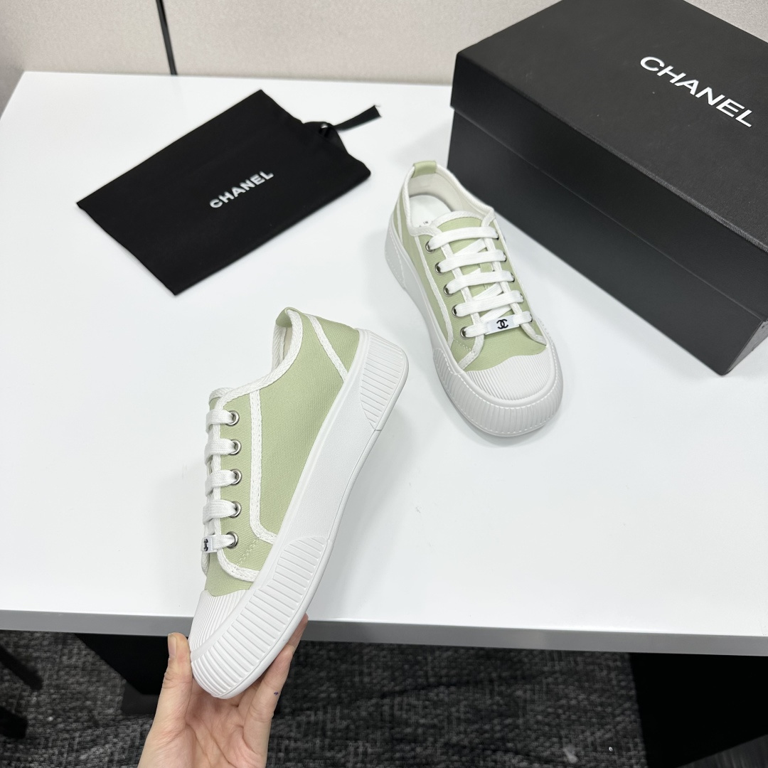 A pair of Chanel luxury green canvas platform sneakers with white ribbed soles and laces displayed on a black box. - Hình 8
