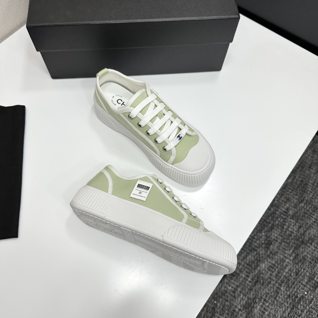 A pair of Chanel luxury green canvas platform sneakers with white ribbed soles and laces displayed on a black box. - Hình 7