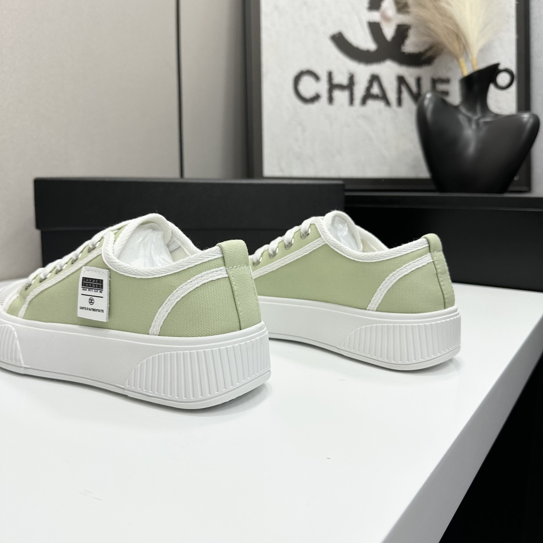 A pair of Chanel luxury green canvas platform sneakers with white ribbed soles and laces displayed on a black box. - Hình 6