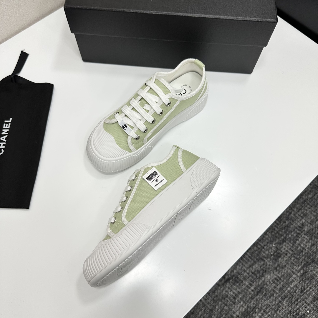 A pair of Chanel luxury green canvas platform sneakers with white ribbed soles and laces displayed on a black box. - Hình 5