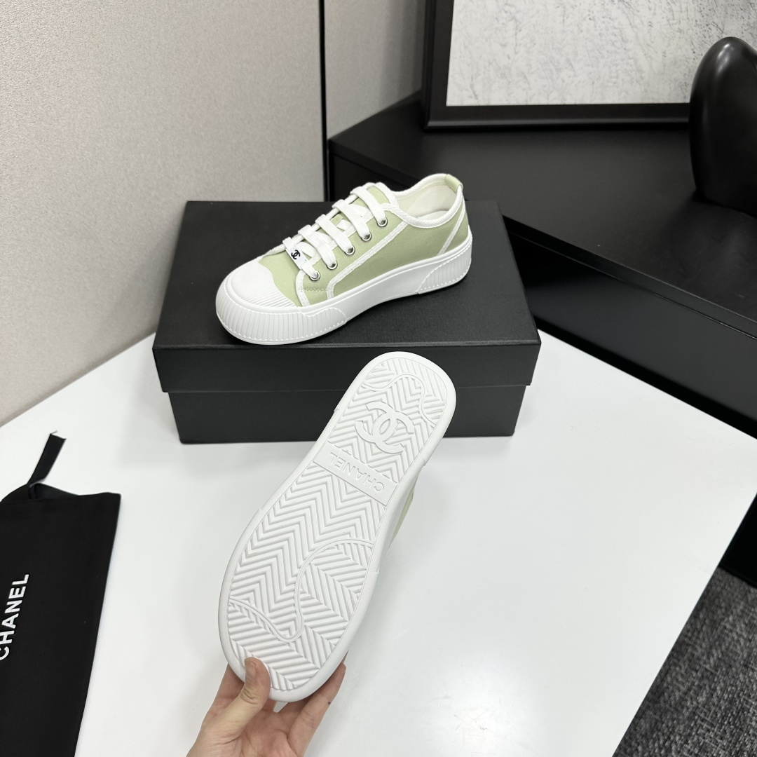 A pair of Chanel luxury green canvas platform sneakers with white ribbed soles and laces displayed on a black box. - Hình 4