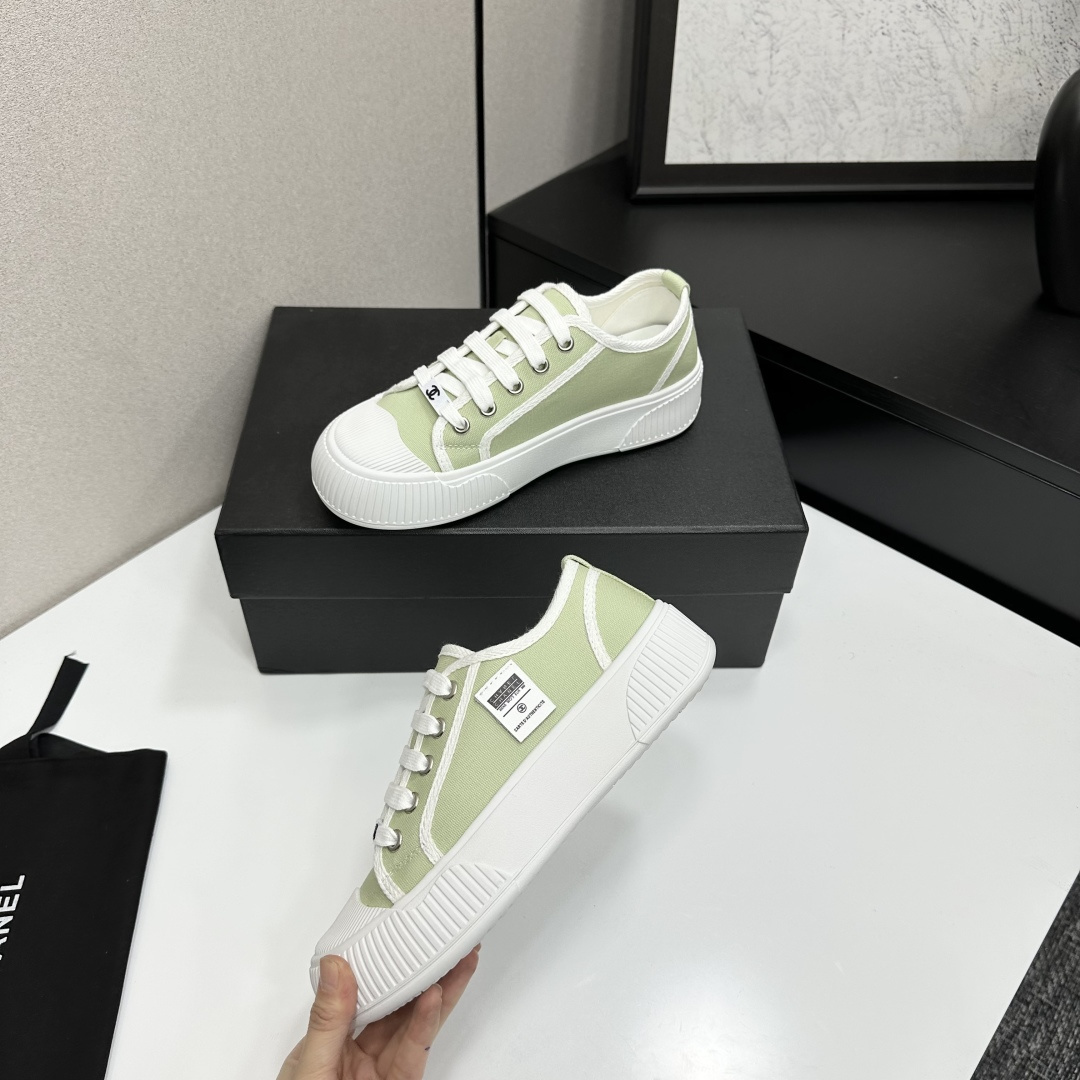 A pair of Chanel luxury green canvas platform sneakers with white ribbed soles and laces displayed on a black box. - Hình 3