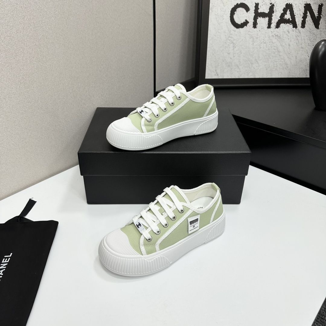 A pair of Chanel luxury green canvas platform sneakers with white ribbed soles and laces displayed on a black box. - Hình 2