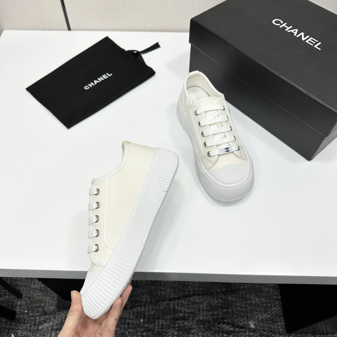 A pair of Chanel white canvas low-top sneakers with a chunky white platform sole resting on a black box. - Hình 9