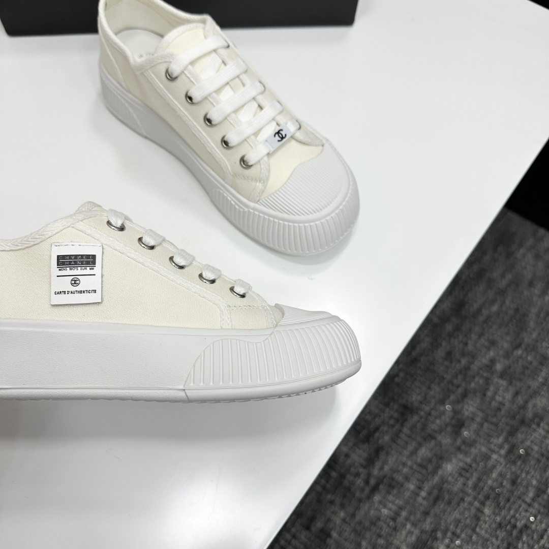 A pair of Chanel white canvas low-top sneakers with a chunky white platform sole resting on a black box. - Hình 8