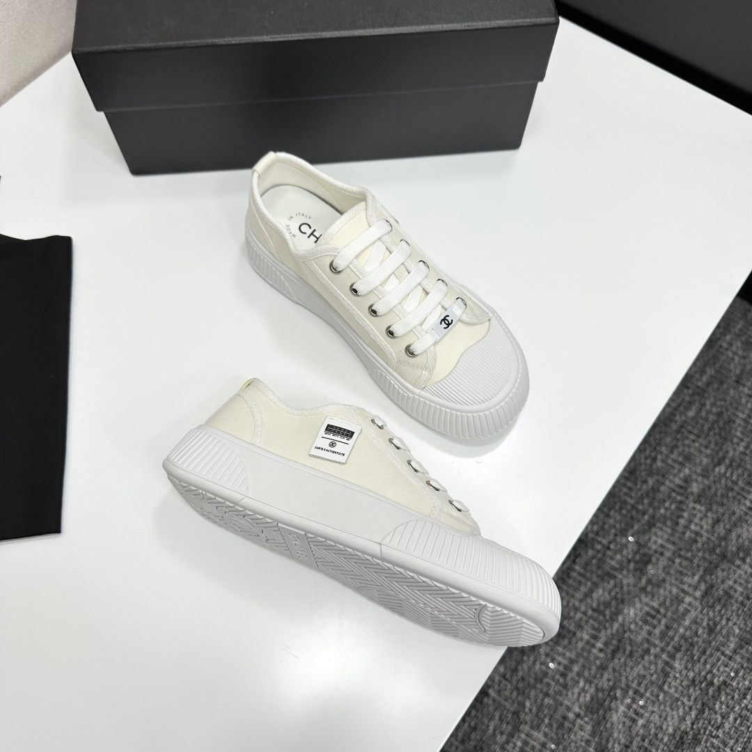 A pair of Chanel white canvas low-top sneakers with a chunky white platform sole resting on a black box. - Hình 7