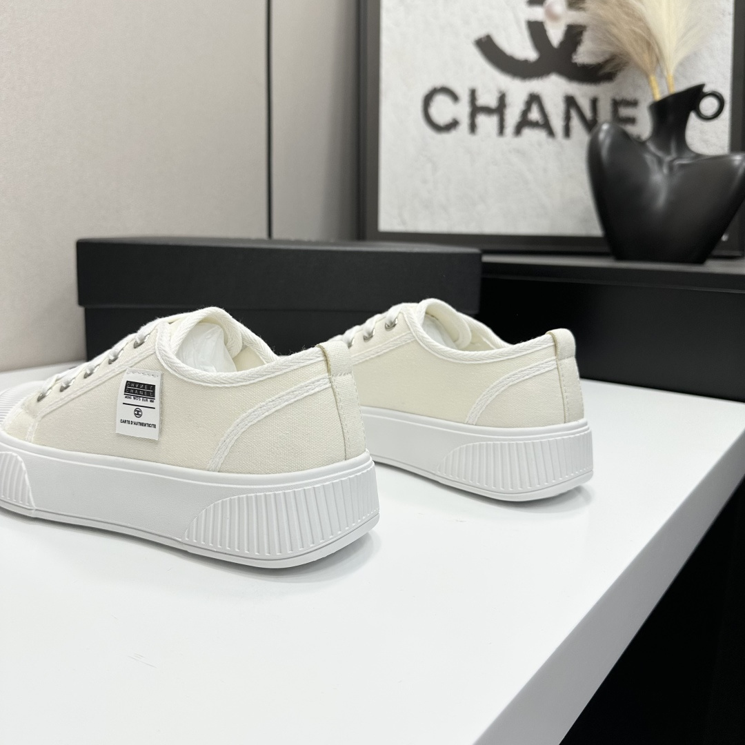 A pair of Chanel white canvas low-top sneakers with a chunky white platform sole resting on a black box. - Hình 6