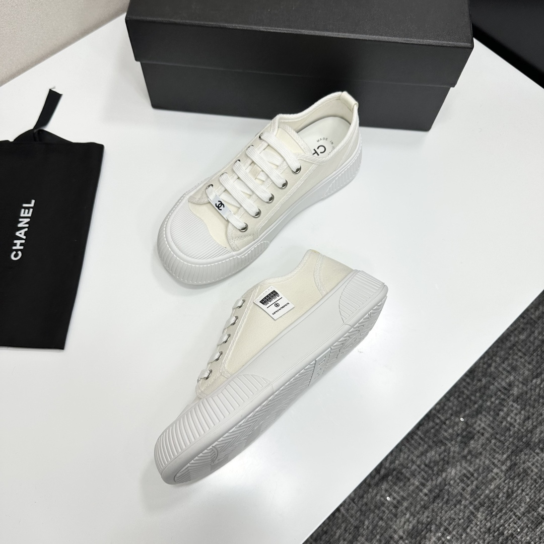 A pair of Chanel white canvas low-top sneakers with a chunky white platform sole resting on a black box. - Hình 5