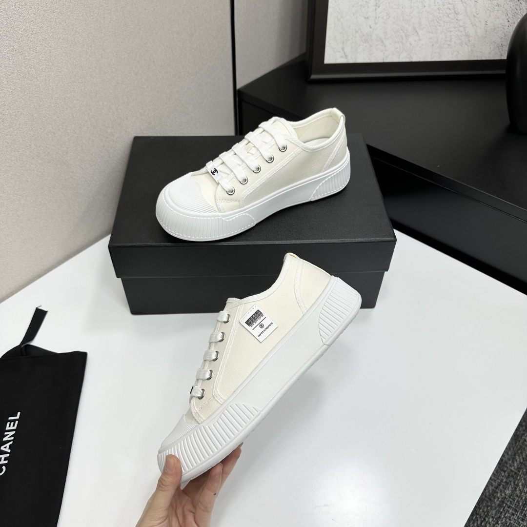 A pair of Chanel white canvas low-top sneakers with a chunky white platform sole resting on a black box. - Hình 3
