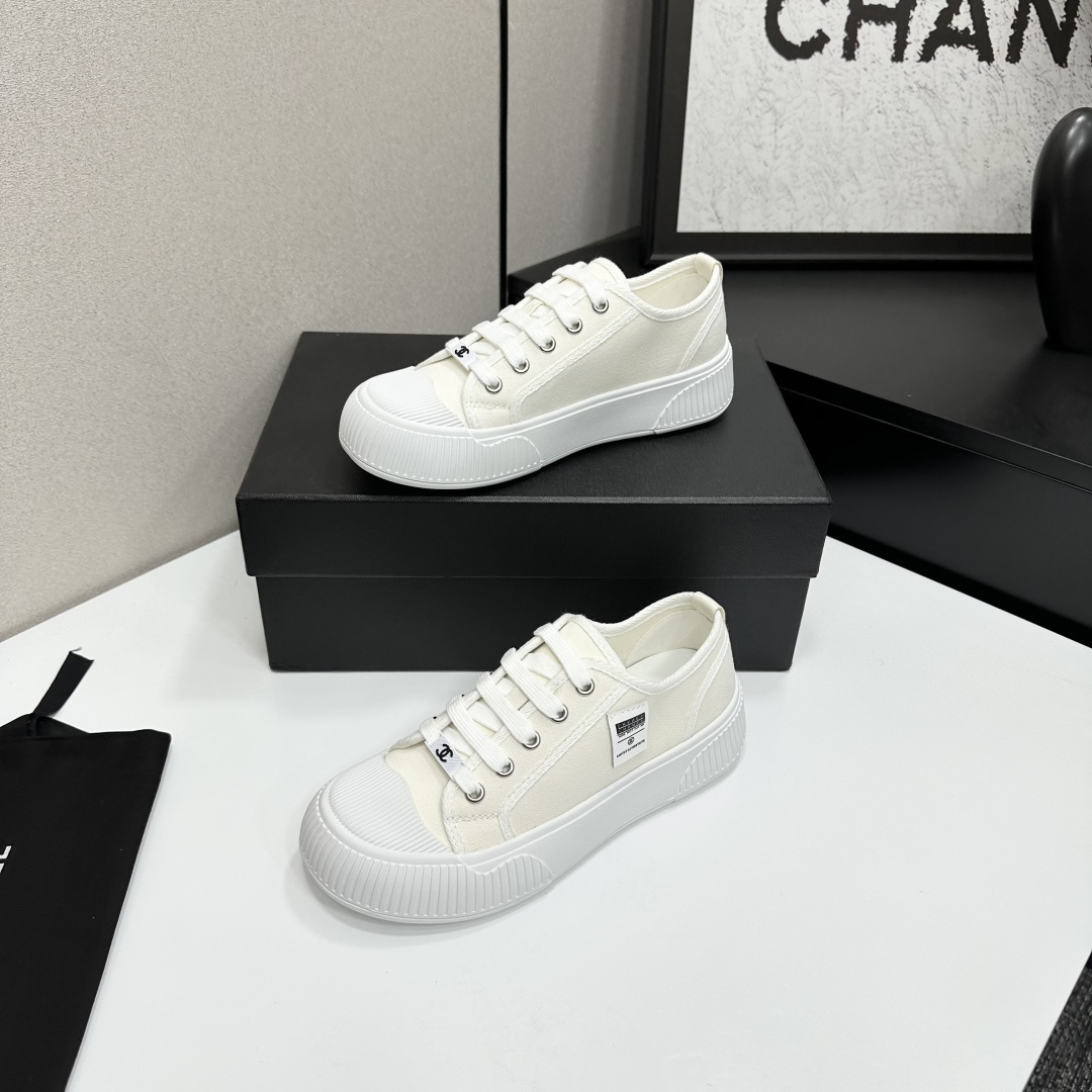 A pair of Chanel white canvas low-top sneakers with a chunky white platform sole resting on a black box. - Hình 2