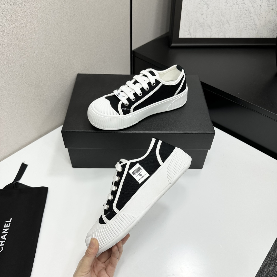 Chanel black and white canvas sneakers with chunky platform ribbed rubber soles displayed on a black box. - Hình 3