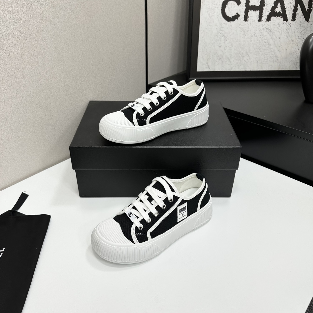 Chanel black and white canvas sneakers with chunky platform ribbed rubber soles displayed on a black box. - Hình 2