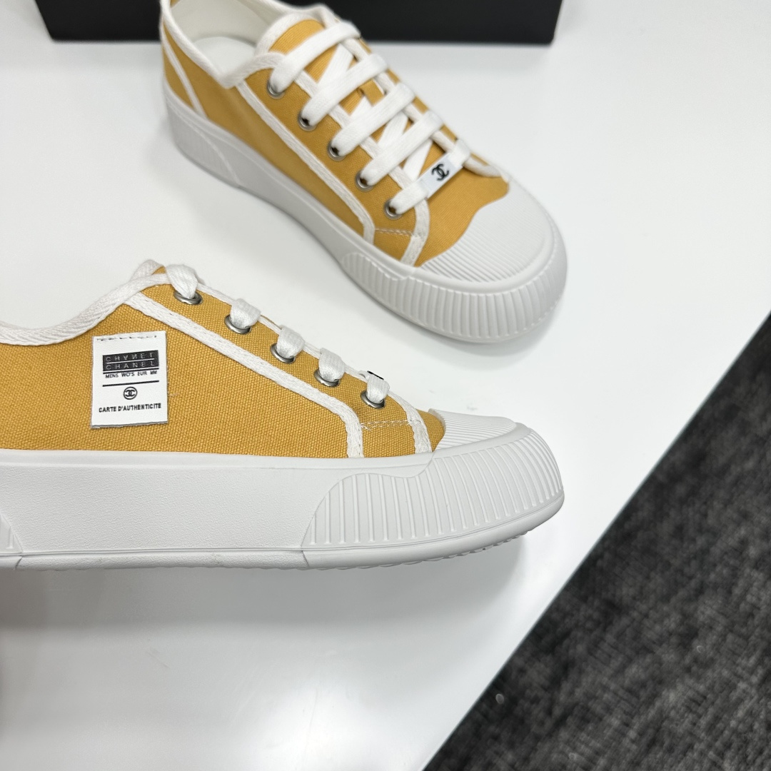 Side view of Chanel yellow canvas platform sneakers with chunky white soles on a black luxury box - Hình 10