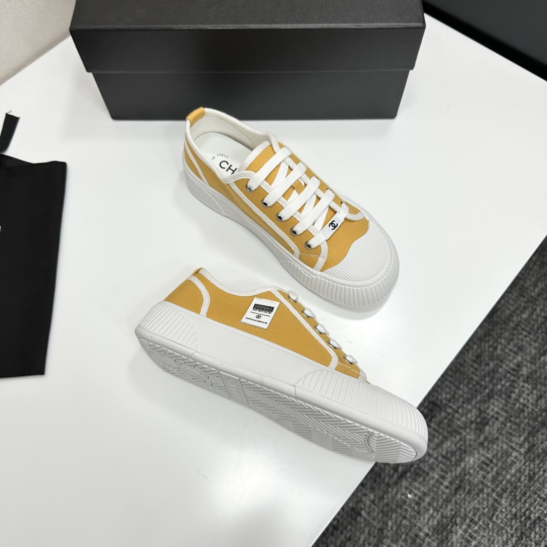 Side view of Chanel yellow canvas platform sneakers with chunky white soles on a black luxury box - Hình 9