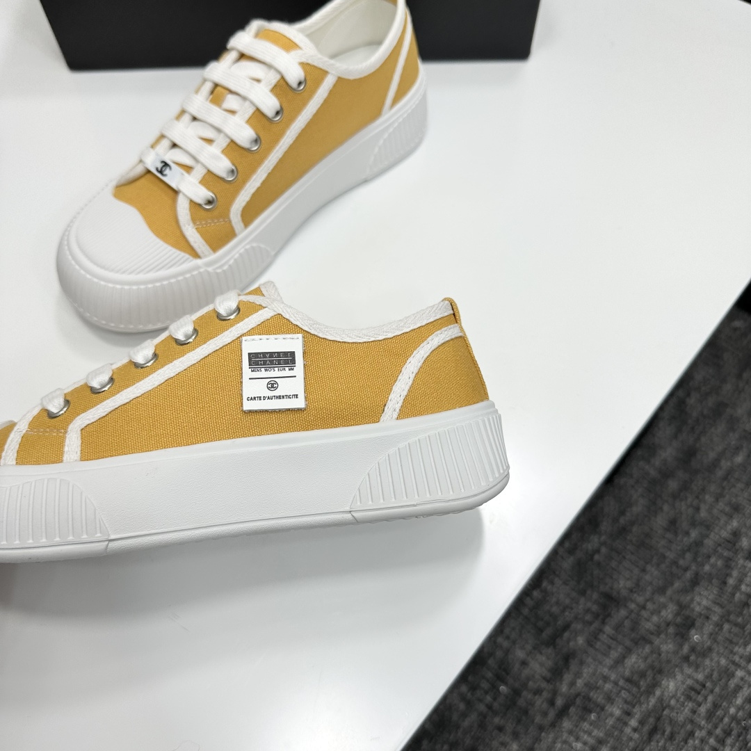 Side view of Chanel yellow canvas platform sneakers with chunky white soles on a black luxury box - Hình 7