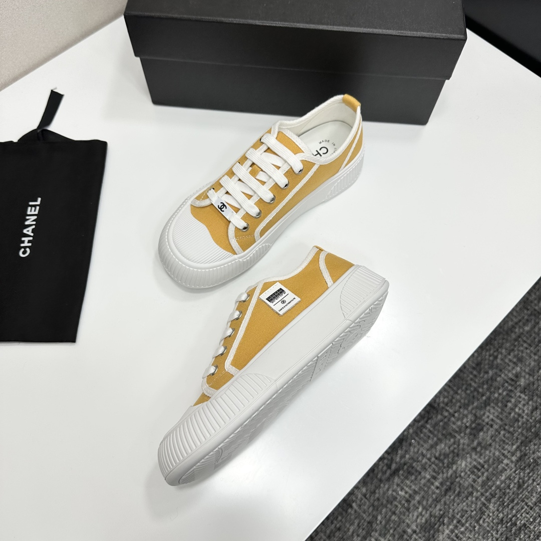 Side view of Chanel yellow canvas platform sneakers with chunky white soles on a black luxury box - Hình 6