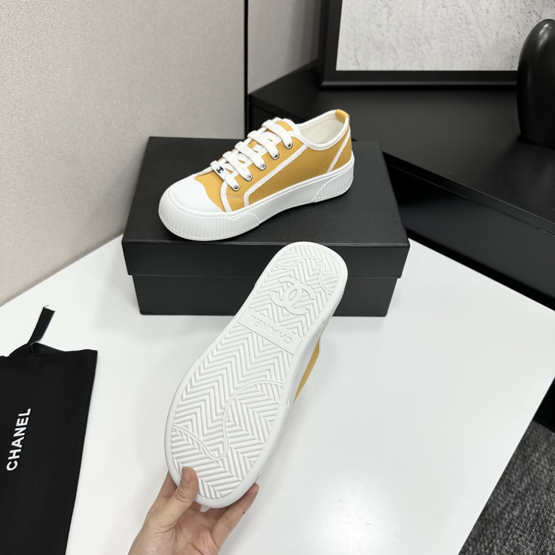 Side view of Chanel yellow canvas platform sneakers with chunky white soles on a black luxury box - Hình 5