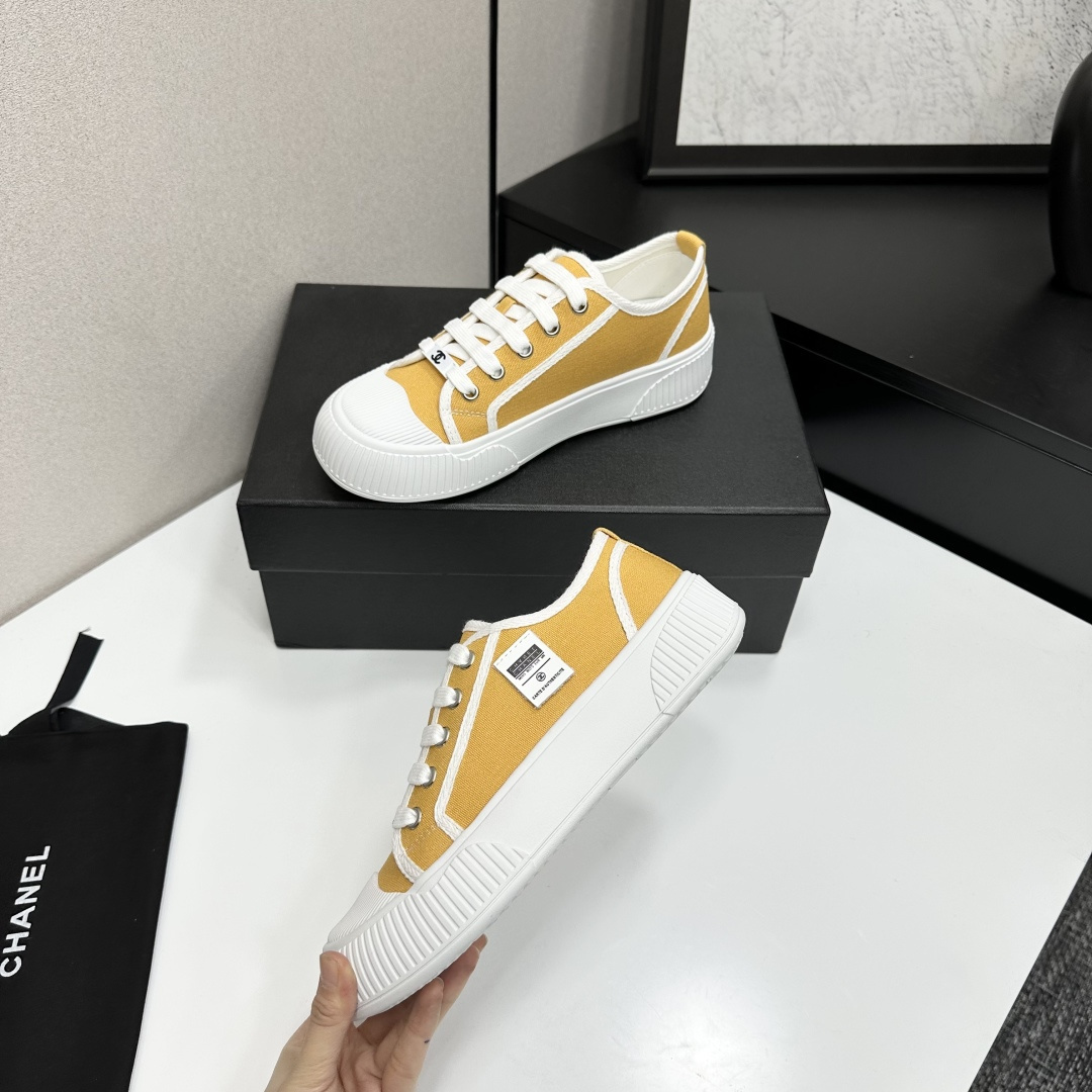 Side view of Chanel yellow canvas platform sneakers with chunky white soles on a black luxury box - Hình 4
