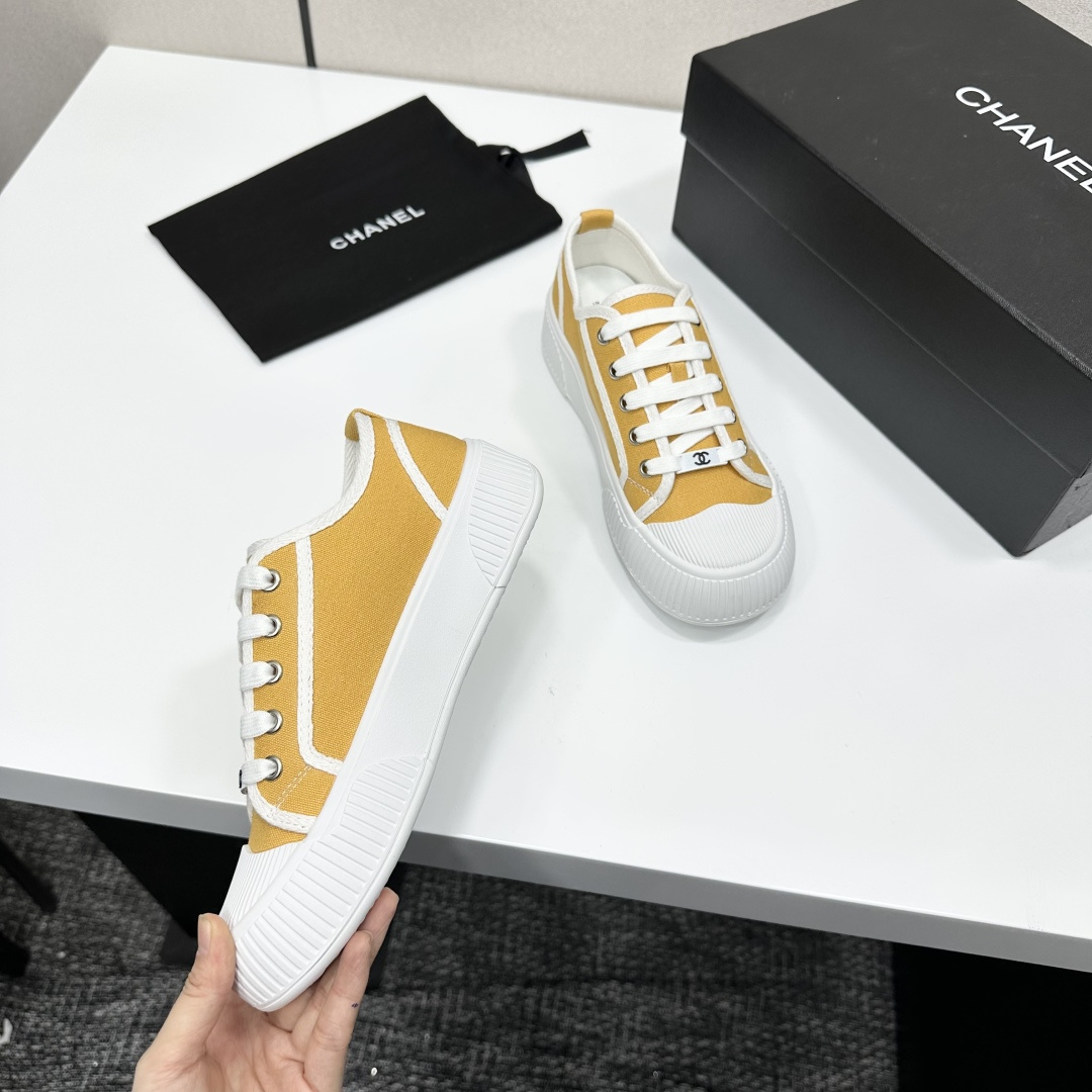 Side view of Chanel yellow canvas platform sneakers with chunky white soles on a black luxury box - Hình 2