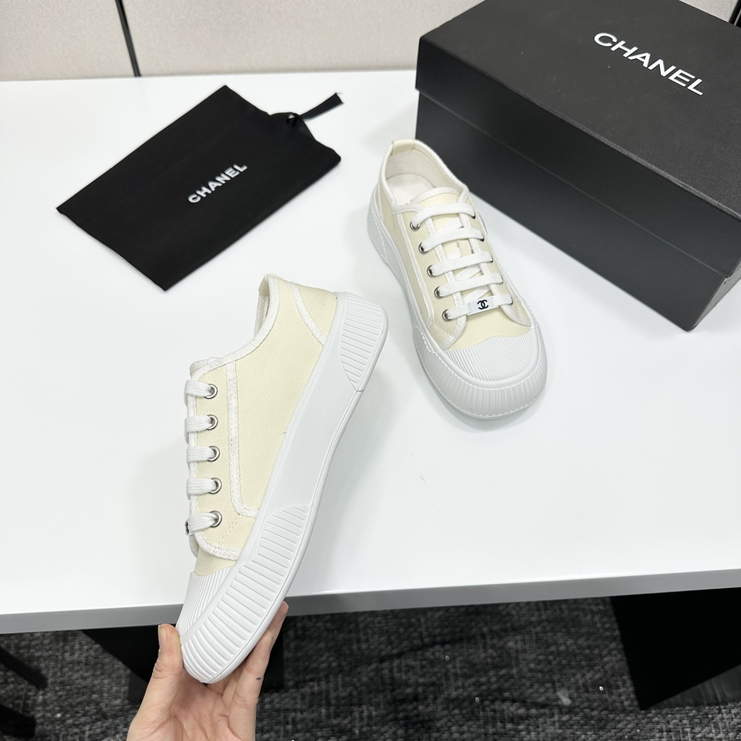 Pair of premium cream canvas low-top sneakers with a chunky white rubber sole and designer logo details displayed on a black box. - Hình 8