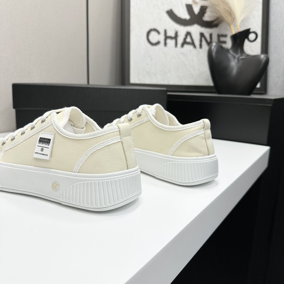 Pair of premium cream canvas low-top sneakers with a chunky white rubber sole and designer logo details displayed on a black box. - Hình 7